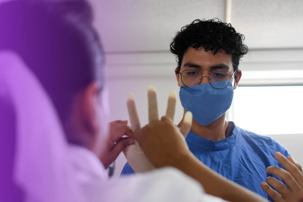 Man wearing glasses and blue face mask giving high-five to person in purple shirt indoors