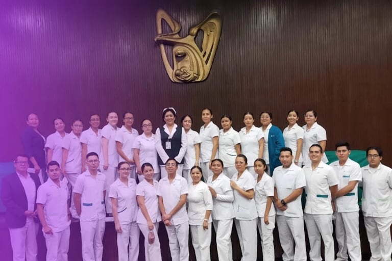 Large group of healthcare professionals in pink and white uniforms standing together under a golden logo on a dark wall