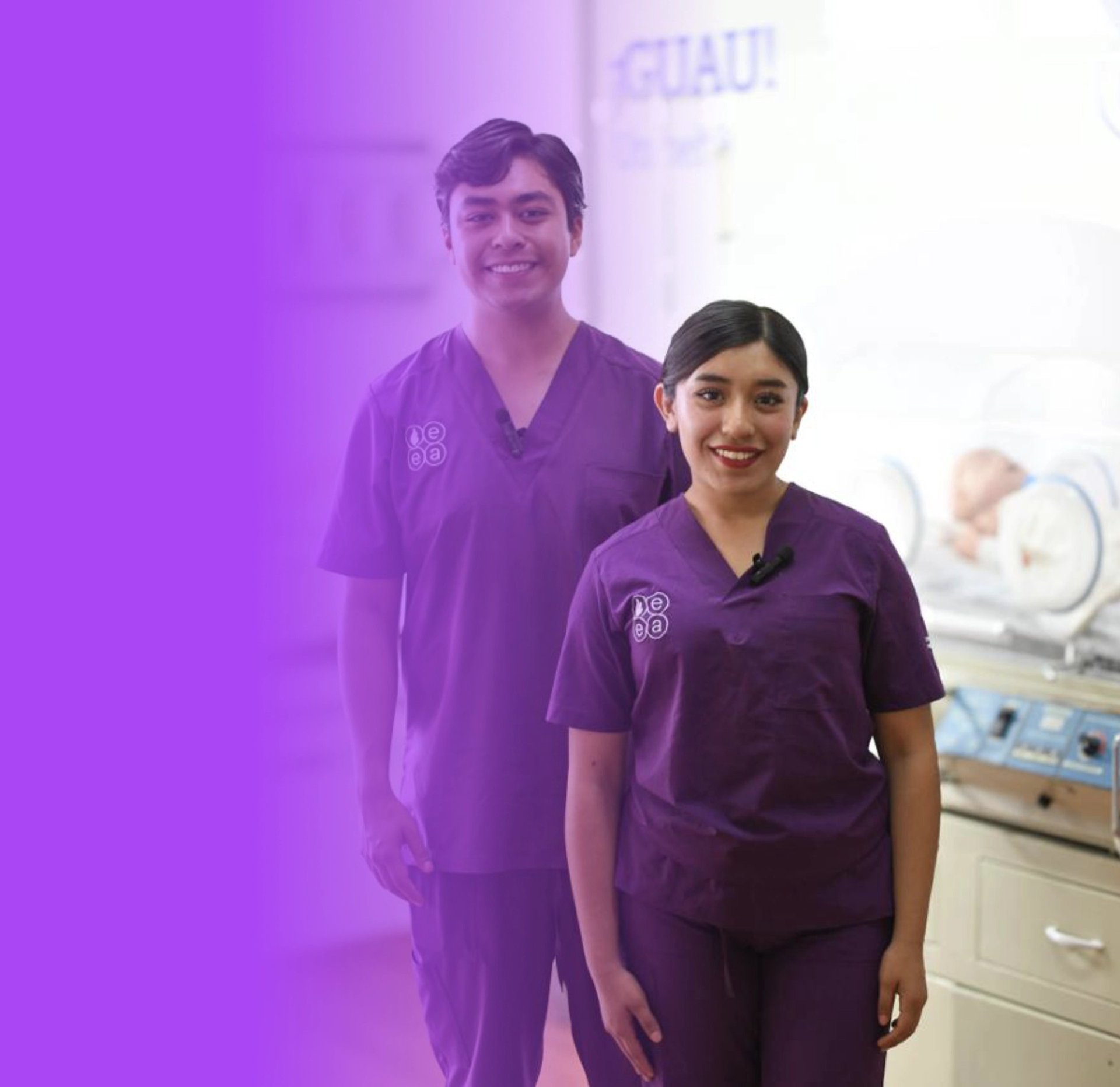 Two healthcare professionals in purple scrubs smiling in a medical clinic setting