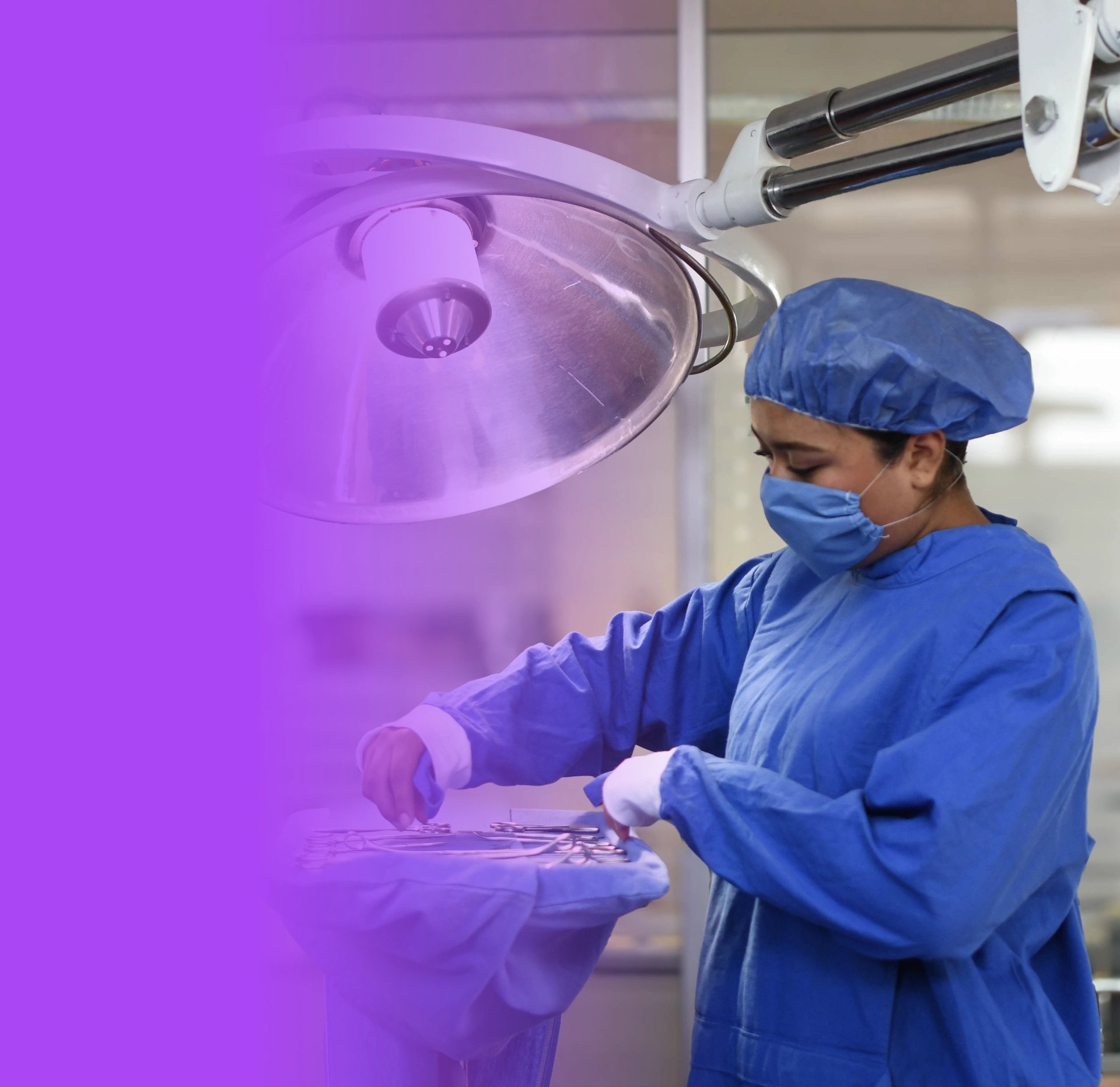 Surgeon in blue scrubs and mask working under surgical light during operating room procedure