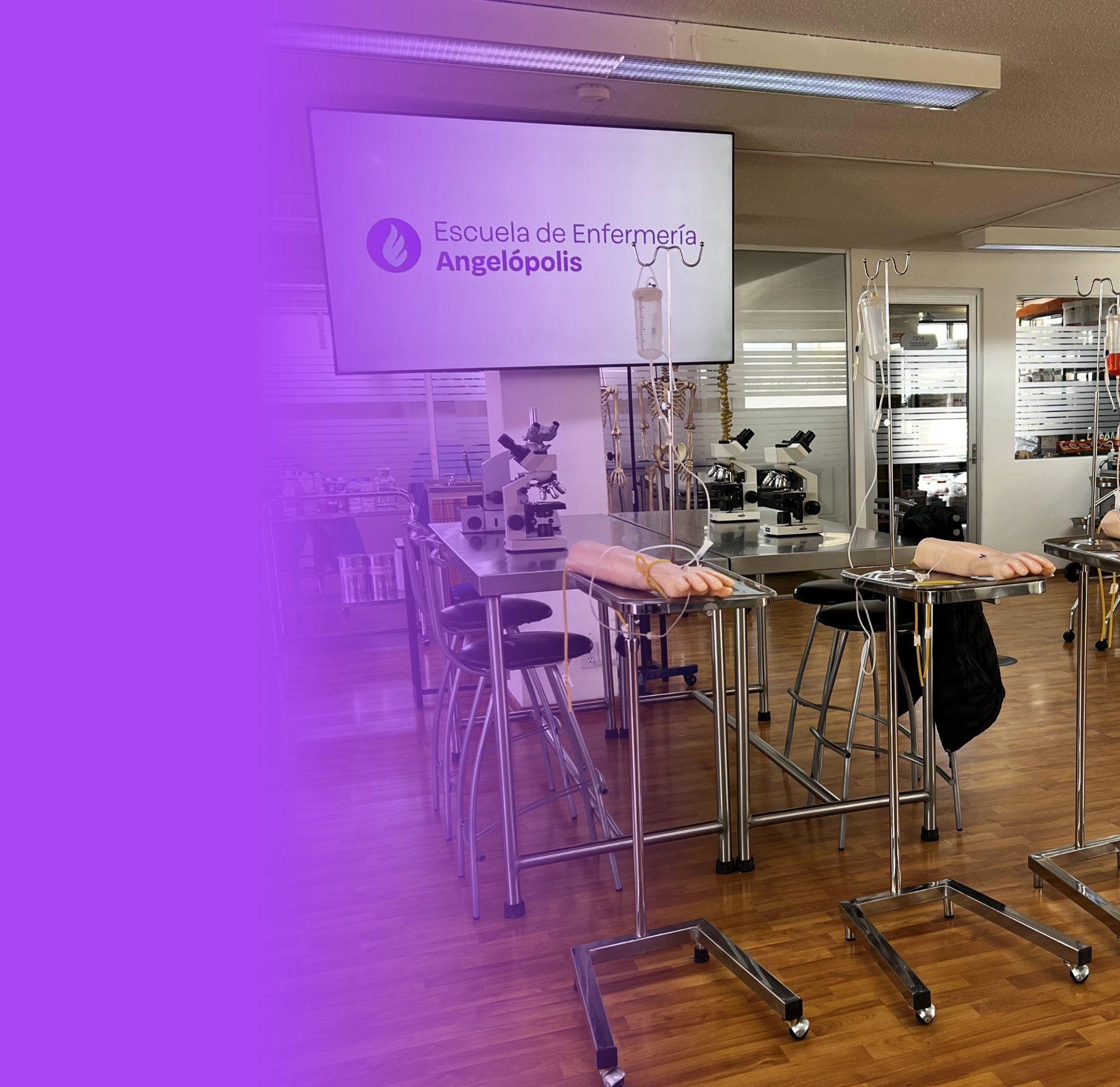 Modern nursing classroom with purple lighting, display screen showing Escuela de Enfermeria Angelopolis, microscopes, and standing workstations